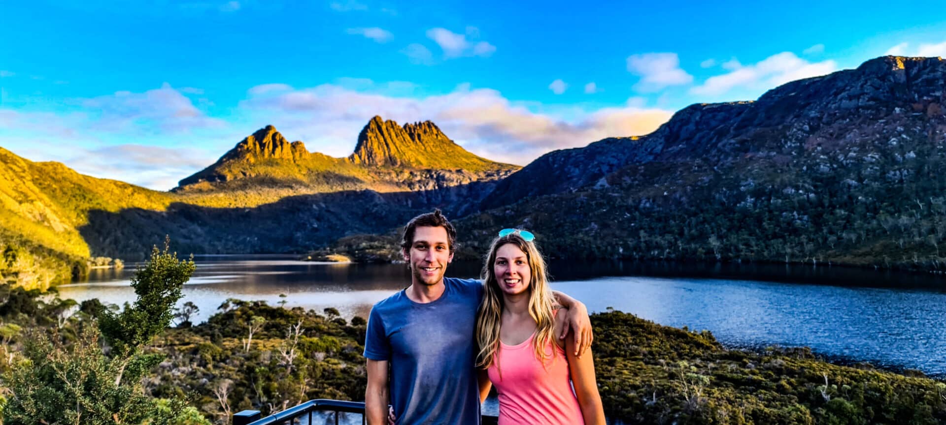 Stefan and Naomi standing in front of Cradle Mountain with the sunsetting behind the mountain
